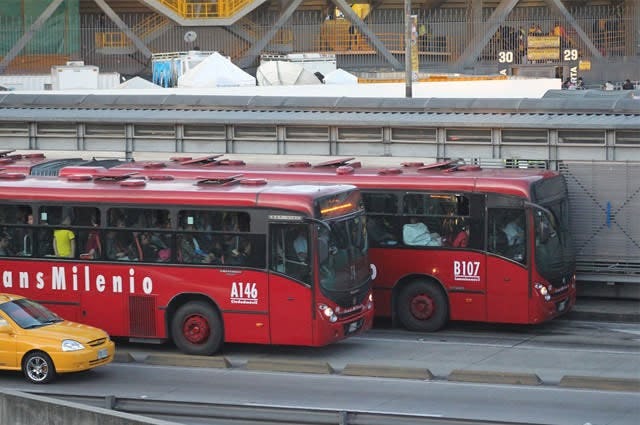 The TransMilenio. Two red coaches with passengers onboard. 