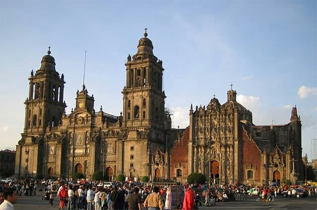 An ancient stone cathedral with towers and central clock in Mexico City