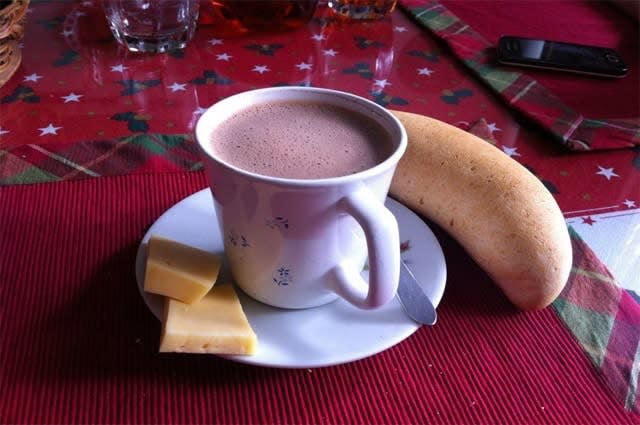 A close up shot of a hot chocolate, served with bread and cheese 